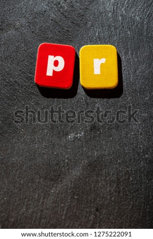 PR letters on paper cardboard. Colored Characters P and R on dark background. Public relations concept.