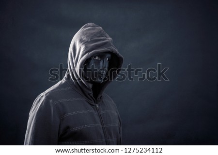 Hooded man with black mask in the dark 