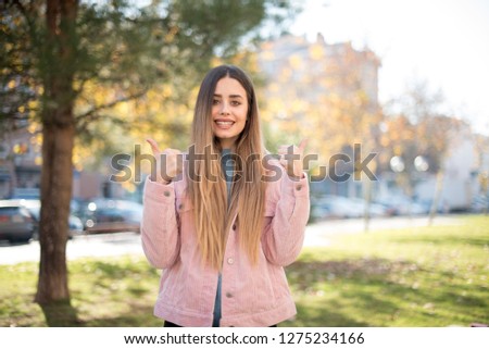 Portrait of a happy young successful woman giving two thumbs up gesture in full disbelief isolated background. Positive human emotion facial expression body language. Funny girl. Good Job. Well done. 