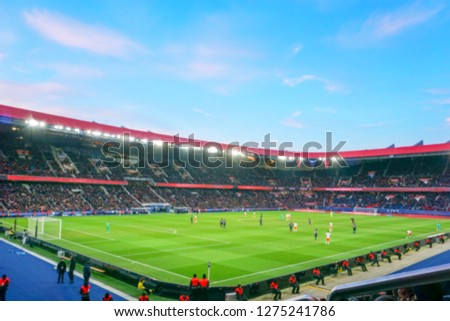 Blurred background of football players playing and soccer fans in match day on beautiful green field with sport light at the stadium. Sports,Athlete,People Concept.Parc des princes,Paris saint german. Royalty-Free Stock Photo #1275241786