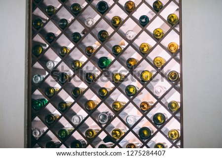 Many glass wine bottles on wine shelves with lighting. Interior in the restaurant. Color photo