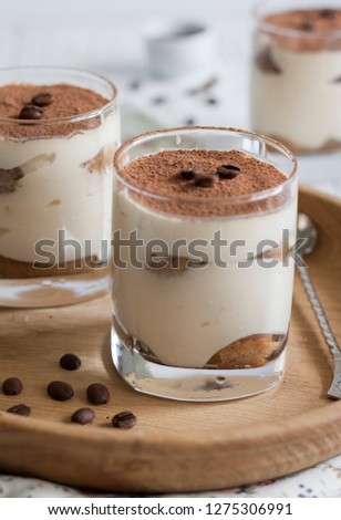 Three portions of traditional italian dessert tiramisu with cacao powder in glasses on white background