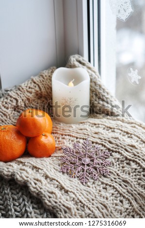 candle and tangerines on the knitted background