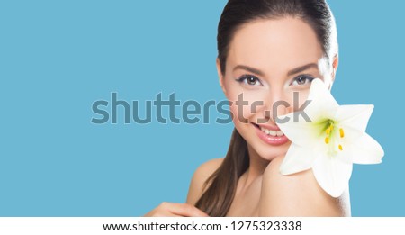 Portrait of brunette beauty in light makeup with white flower.