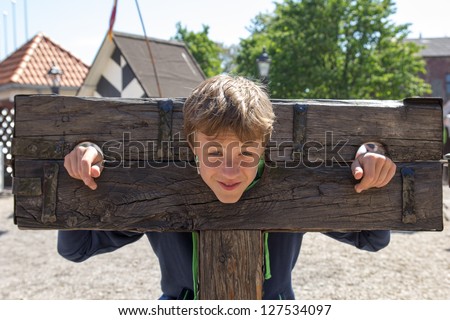 a boy trapped in a medieval torture device