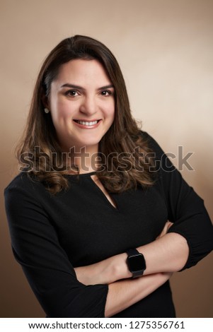 Young woman with crossed arms on studio brown background