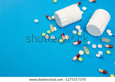 Blank place frame for text. Pills, capsules, plastic medicine bottle with a white label. Paper blue background. Top view.