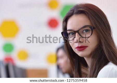 Beautiful female student wearing glasses working at computer lab at university campus interior. Looking into camera.