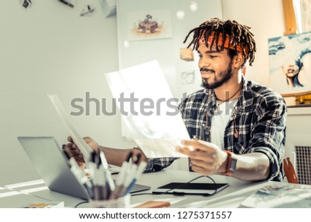 Squared shirt. Bearded graphic designer with dreadlocks wearing squared shirt and red headband