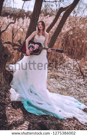 Beautiful romantic european girl with guitar with flowers inside, posing outdoors. Concept of music and nature. Spring time. Fashion retouched shot