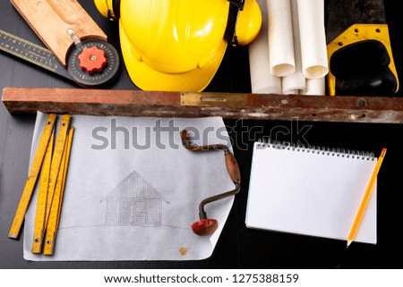 Tools and notes for a carpenter on a workshop table. Accessories for a production worker. Dark background.