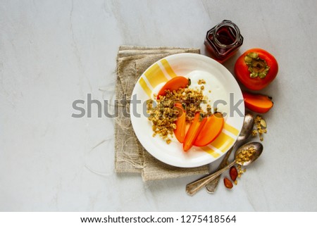 Healthy greek yogurt with granola and fresh persimmon flat lay. Seasonal fall breakfast