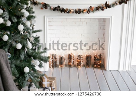 Christmas interior with a Christmas tree decorated with white balls and a decorative white fireplace.