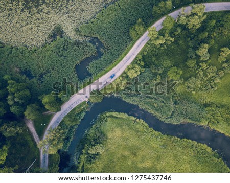 Aerial Photo of Car Driving on the Road going by the River under the Trees, Top Down View in Early Spring on Sunny Day - Concept of Peaceful Life in Countryside in Harmony and Traveling, Freedom