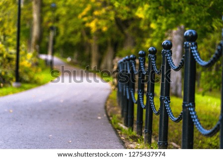 Colorful Photo of the Road in a Park, Between Woods - Closeup view of the Chain Fence with Blurred Background with Space for Text, Sunny Autumn day