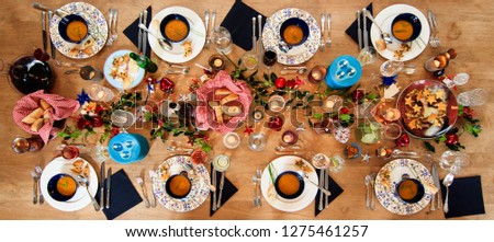 LARGE WOODEN TABLE, PICTURE FROM ABOVE TAKEN HORIZONTAL WITH EIGHT DISHES IN A WARM CHRISTMAS AMBIANCE. CANDLES, WAX-LITS, DECORATION, BREAD, WINE, WATER,SOUP. 