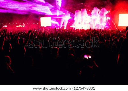 Bright stage lights and confetti concert crowd in front of area