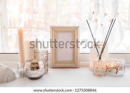 Details of still life in the home interior. Aroma stick, interior items, candles, frame for text, Moody. Cosy autumn winter light concept. Copy space, monochrome background