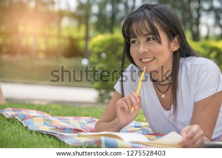 Young woman college student doing her homework in the park on a sunny day
