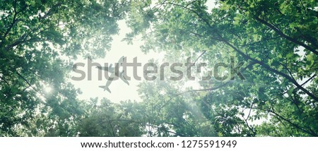 Eco-friendly air transport concept. The plane flies in the sky against the background of green trees. Environmental pollution. Harmful emissions Royalty-Free Stock Photo #1275591949