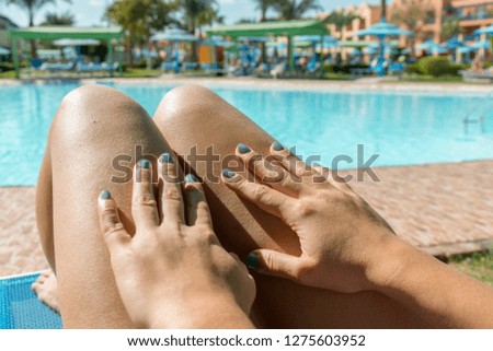 Beautiful young slim woman legs sunbathe near swimming pool. Girl sunbathing by the pool