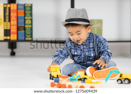 One year old Asian baby boy smile and sitting on floor play the toys happily enjoy in the book room.