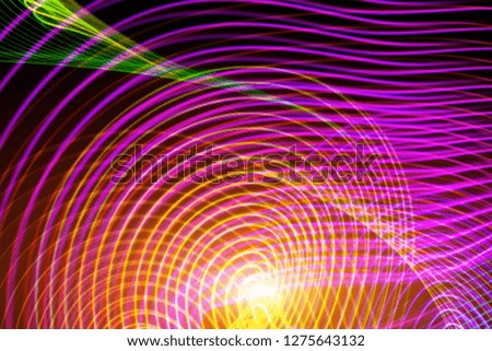Abstract yellow, pink, blue and green neon glowing crossing lines pattern. Dark  background of colorful neon glowing light shapes.