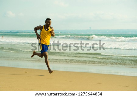 young attractive fit athletic and strong black African American man running at the beach training hard and sprinting on sea water in professional athlete lifestyle and ripped runner workout 