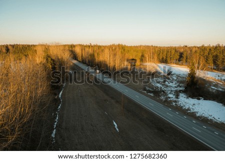 White trucks arriving on the asphalt road in rural landscape in the rays of the sunset - Image 