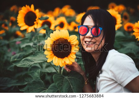 Beautiful smile asian woman with sunglasses in the sunflower field.Vintage Style