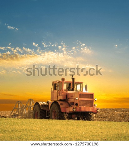 Tractor cultivating the field on sunrise