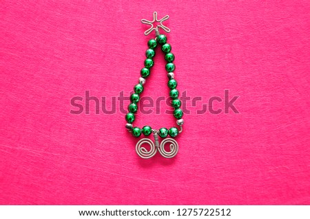 A christmas tree made out of beads and wire on a pink background