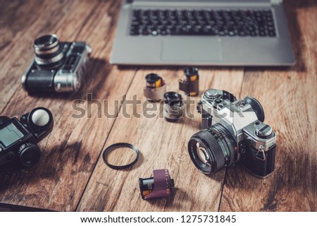 Analog camera, film rolls and vintage photography accessories along with modern equpment and laptop.