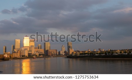 View of Canary Wharf buildings at sunset clouds and sun reflections in London, United Kingdom, Europe