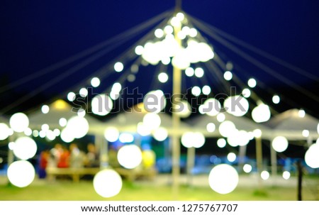 ฺBlur picture of circular lamps hanging above a triangle tent around a camp. Bokeh concept.