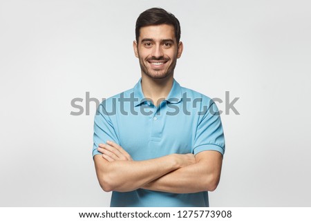 Smiling handsome man in blue polo shirt standing with crossed arms isolated on gray background Royalty-Free Stock Photo #1275773908