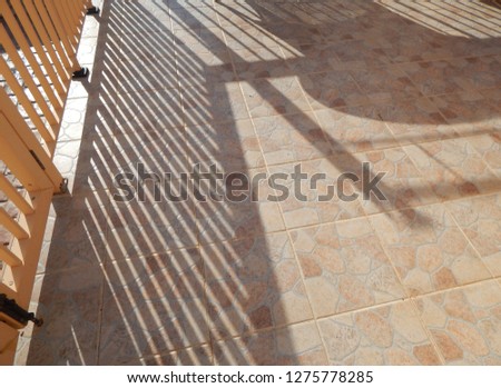 Metal railings throwing angled shadows across tiled patio.
