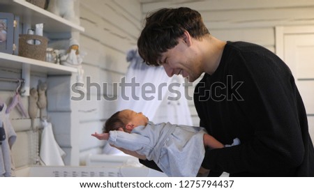 young father holding and smiling his new born infant baby