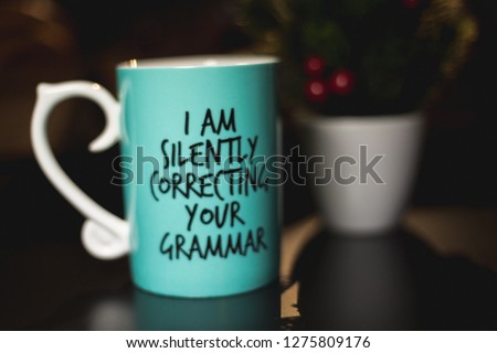 "I am silently correcting your grammar" coffee mug for comedy and education purposes. Turquoise mug on black ground with cozy background. 