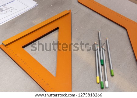 
Yellow wooden triangles and coloured pencils on the desktop ，Vintage wooden set square in the form of a triangle with two round holes used for technical and engineering drawings to obtain a perfect r