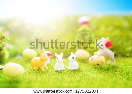 Little bunny toys on green meadow with a colorful easter eggs.