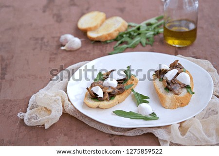 Light snack, crispy bruschetta with champignons, arugula and mozzarella. Italian Cuisine.