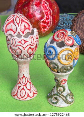 Interesting ceramic egg holders with open lids on green background. Closeup