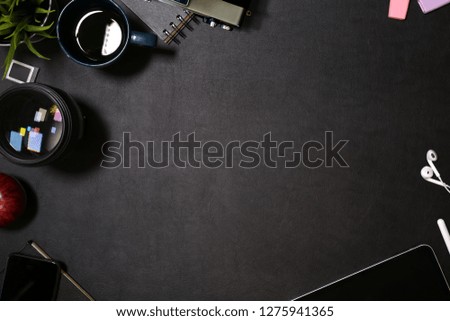 Creative dark leather desk with tablet, lens and designer gadget