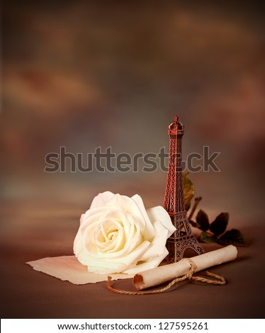 Photo of beautiful romantic still life on dark grunge background, love letter, old paper scroll with romantic message decorated with small Eiffel tower, Valentine day in Paris, honeymoon in France