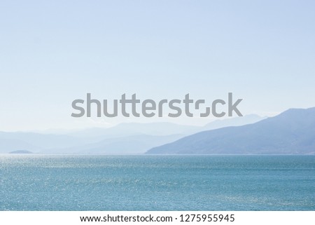 abstract picturesque scenic landscape of big lake natural reservoir foreground and mountain silhouettes in fog with sky background in sun rise morning time 