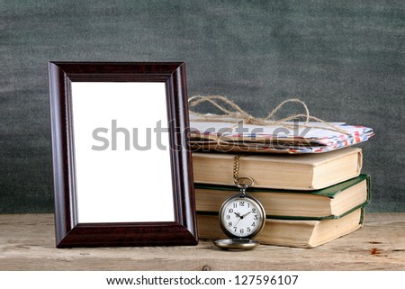 Photo frame and pile of old books on wooden table