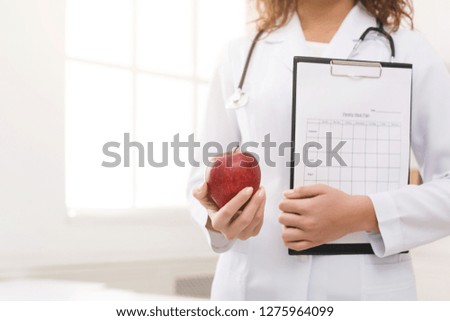 Diet plan. Unrecognizable female nutritionist holding apple and diet plan in office, copy space