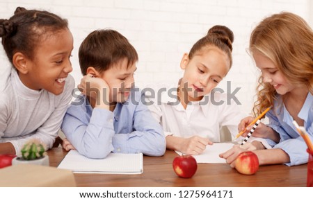 Multiracial children drawing together in classroom during lesson