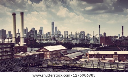 CITYSCAPE FROM BROOKLYN WITH OLD FACTORIES AND CHIMNEYS WITH THE SKYLINE OF NEW YORK CITY AND THE BROOKLYN BRIDGE IN THE BACKGROUND. VINTAGE COLOURS LIKE RED AND BROWN, PANORAMA VIEW ,CLOUDED BLUE SKY
